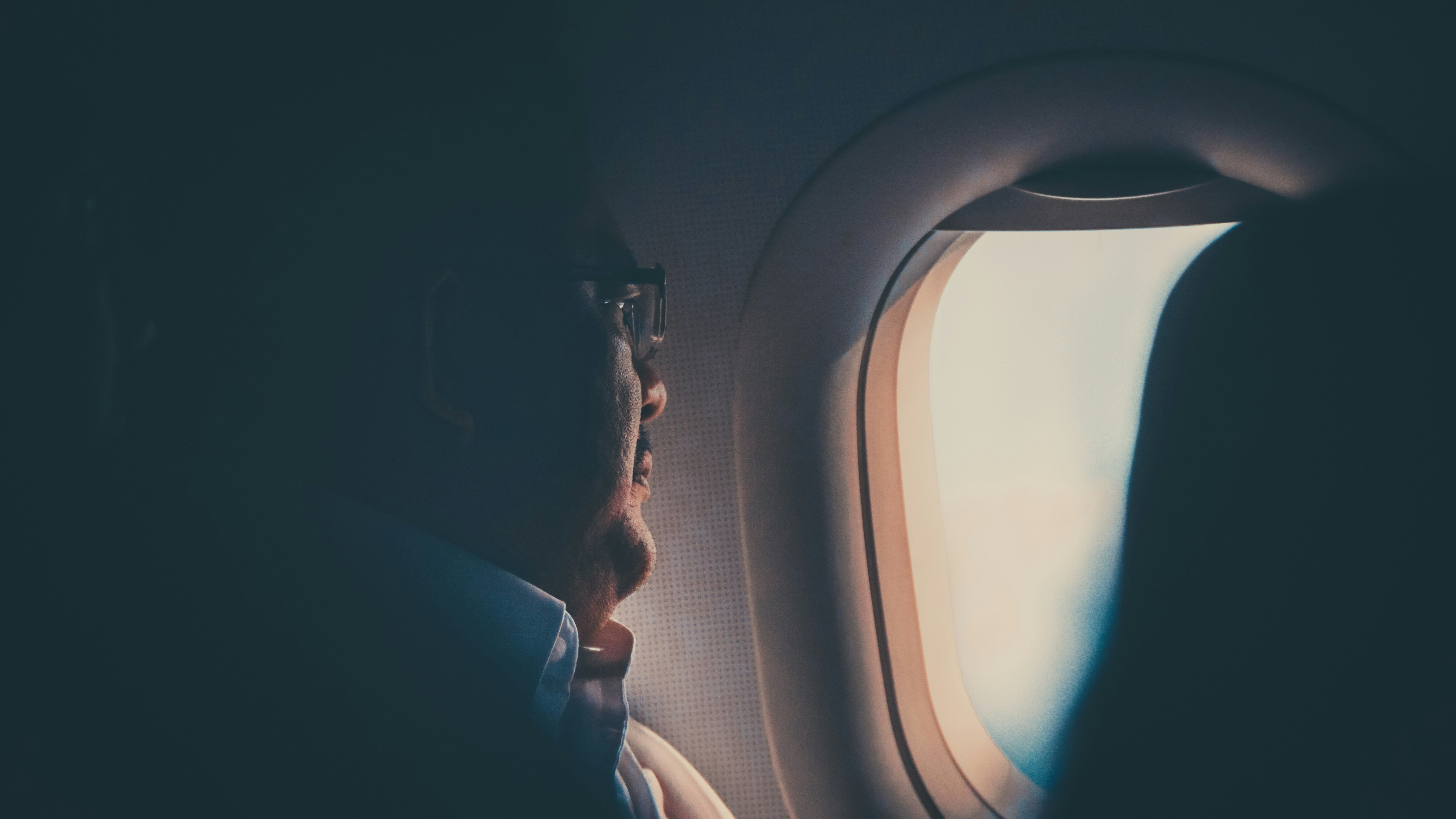 closeup photo of man wearing white collared shirt sitting beside glass window